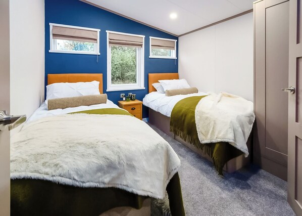 A hotel room with two beds, a wooden headboard, a nightstand, and a door.