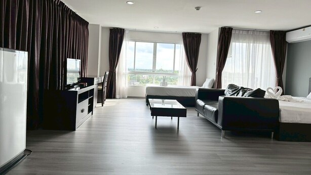 Een moderne hotelkamer met een groot raam, een bank, een bed, een televisie en een bureau.