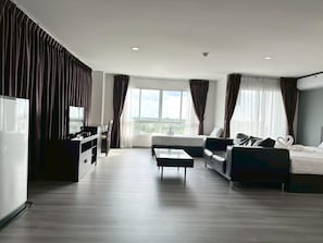 Et moderne hotelværelse med et stort vindue, en sofa, en seng, et fjernsyn og et skrivebord.