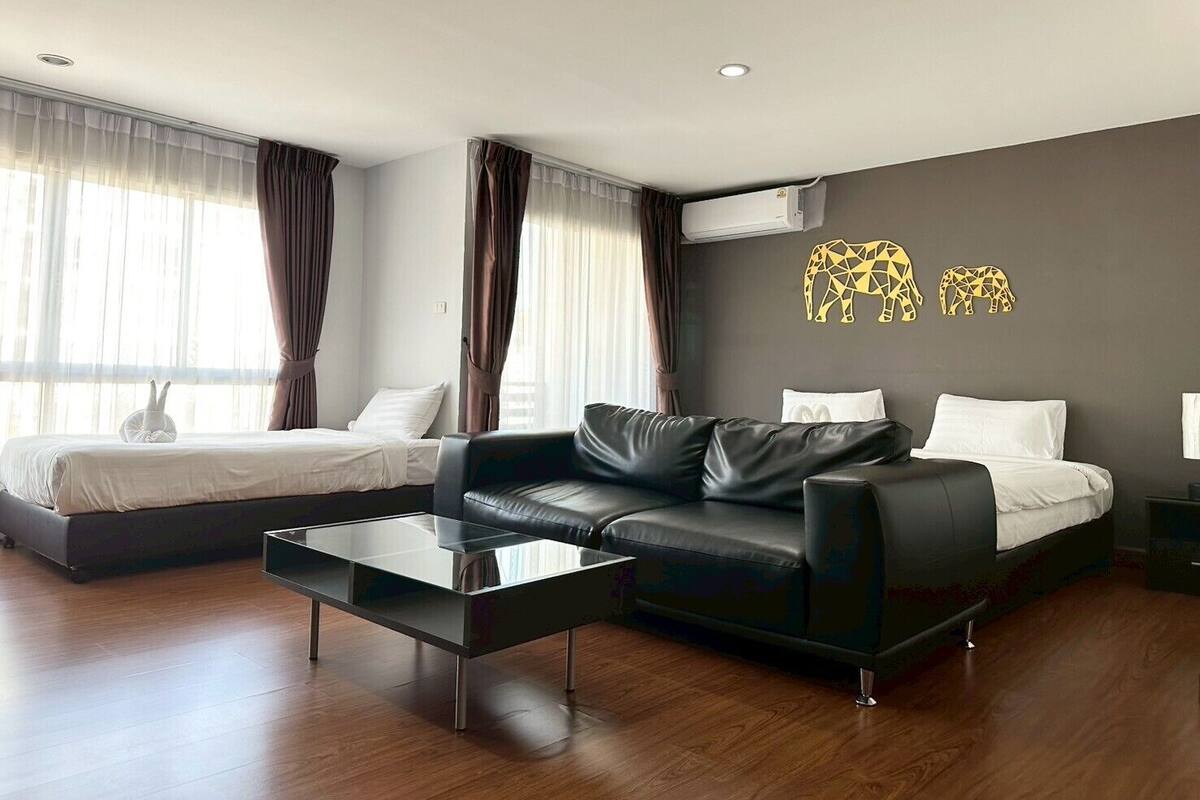 Een moderne hotelkamer met een bed, een bank, een salontafel en een wandairconditioner.