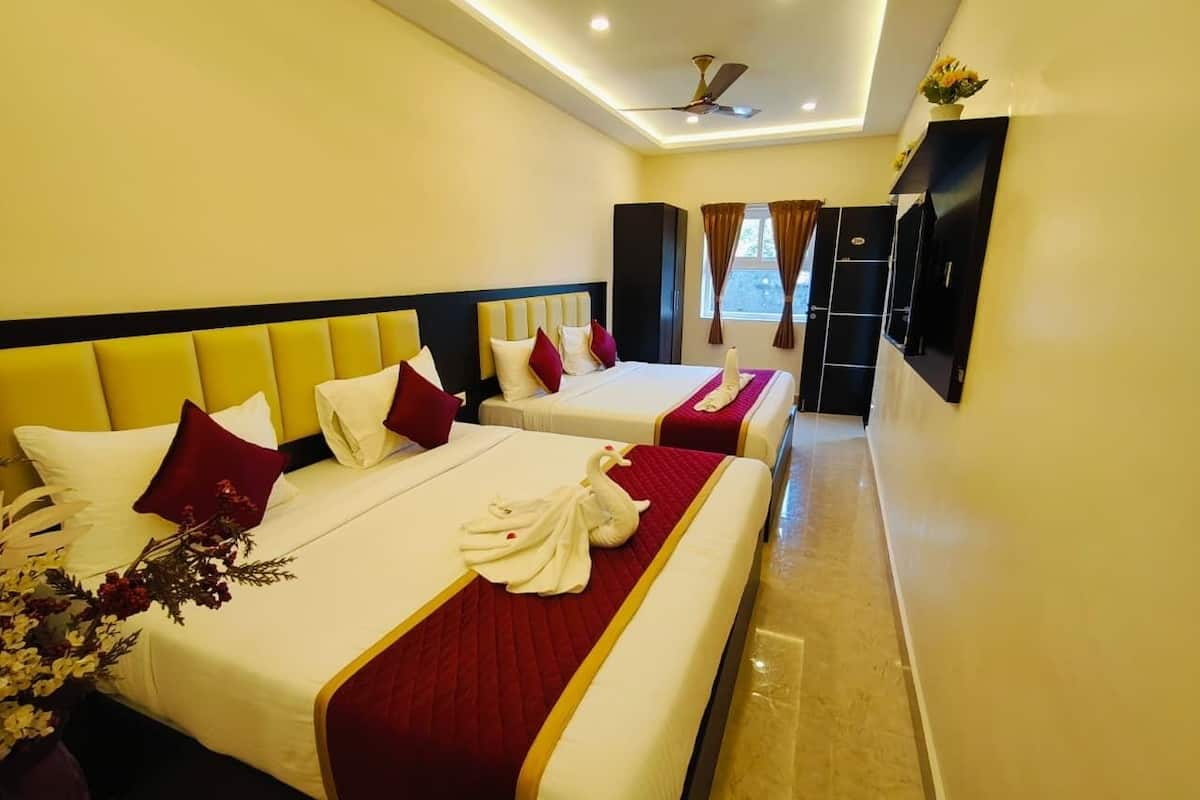 Habitación de hotel con dos camas, cada una con una colcha rojo y blanco, y un ventanal con cortinas.