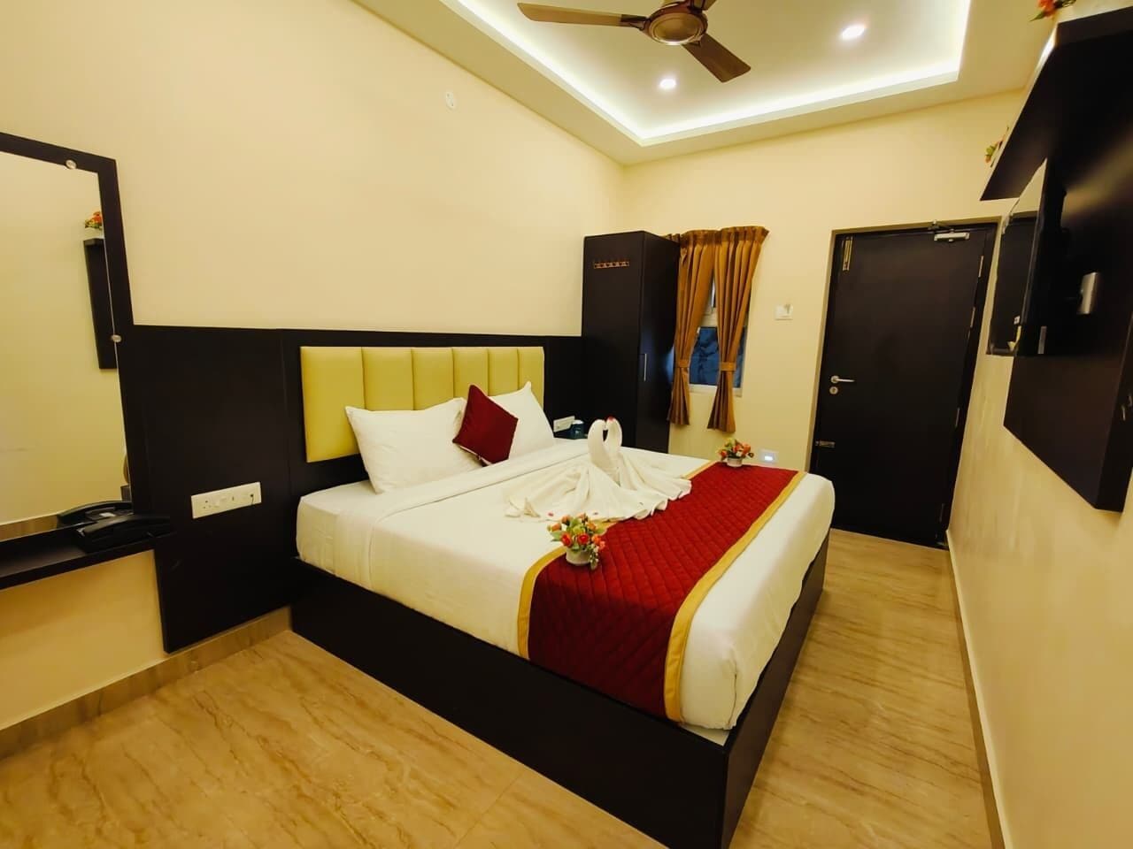 A hotel room with a bed, a ceiling fan, a wardrobe, and a door.
