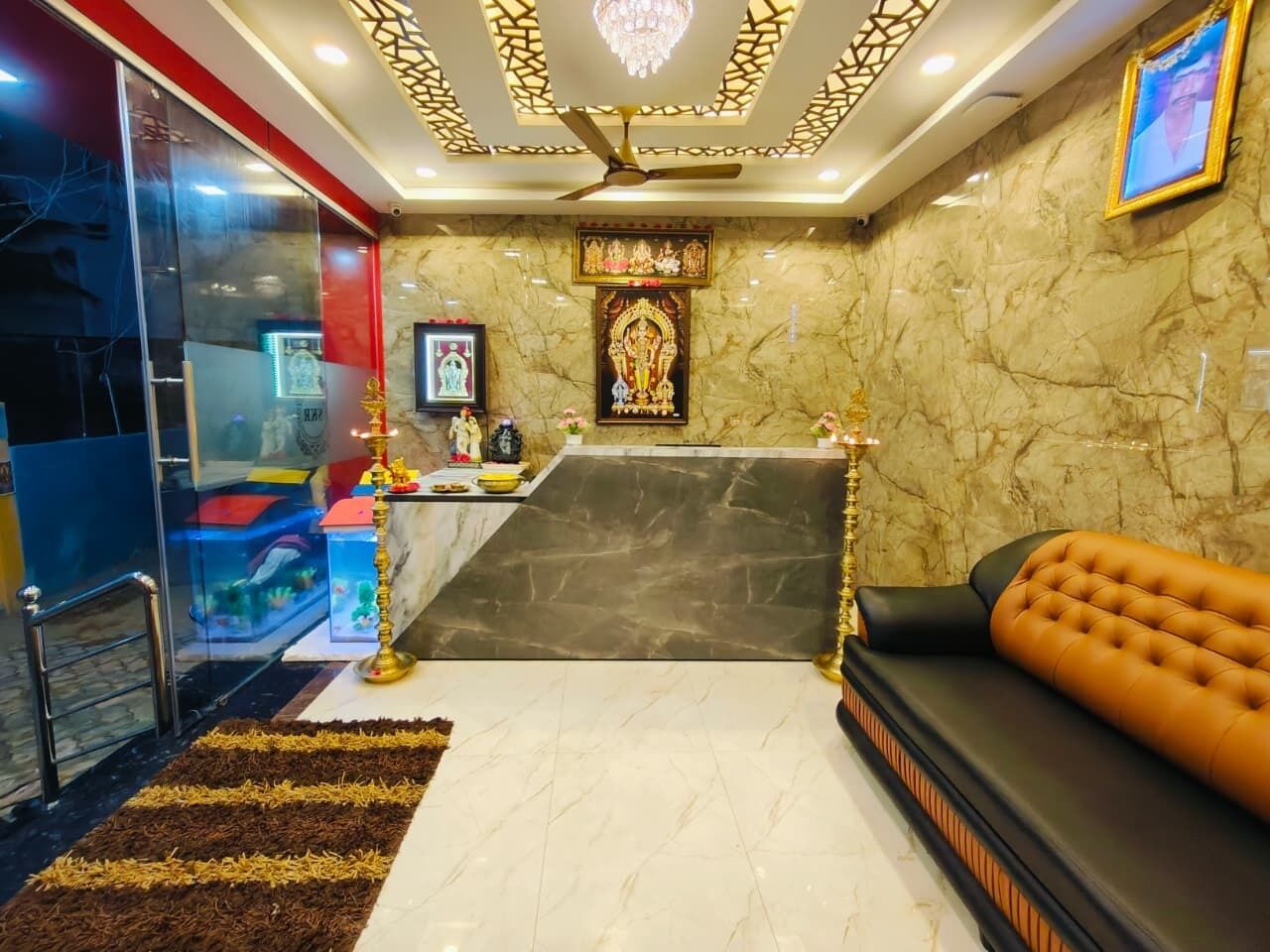 A reception area with a marble floor, a sofa, a reception desk, and a chandelier.