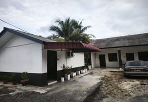 A two-story building with a red roof, a car parked in the driveway, and a palm tree in the background. - OYO 91244 Aufa Chalet (Kuala Terengganu)