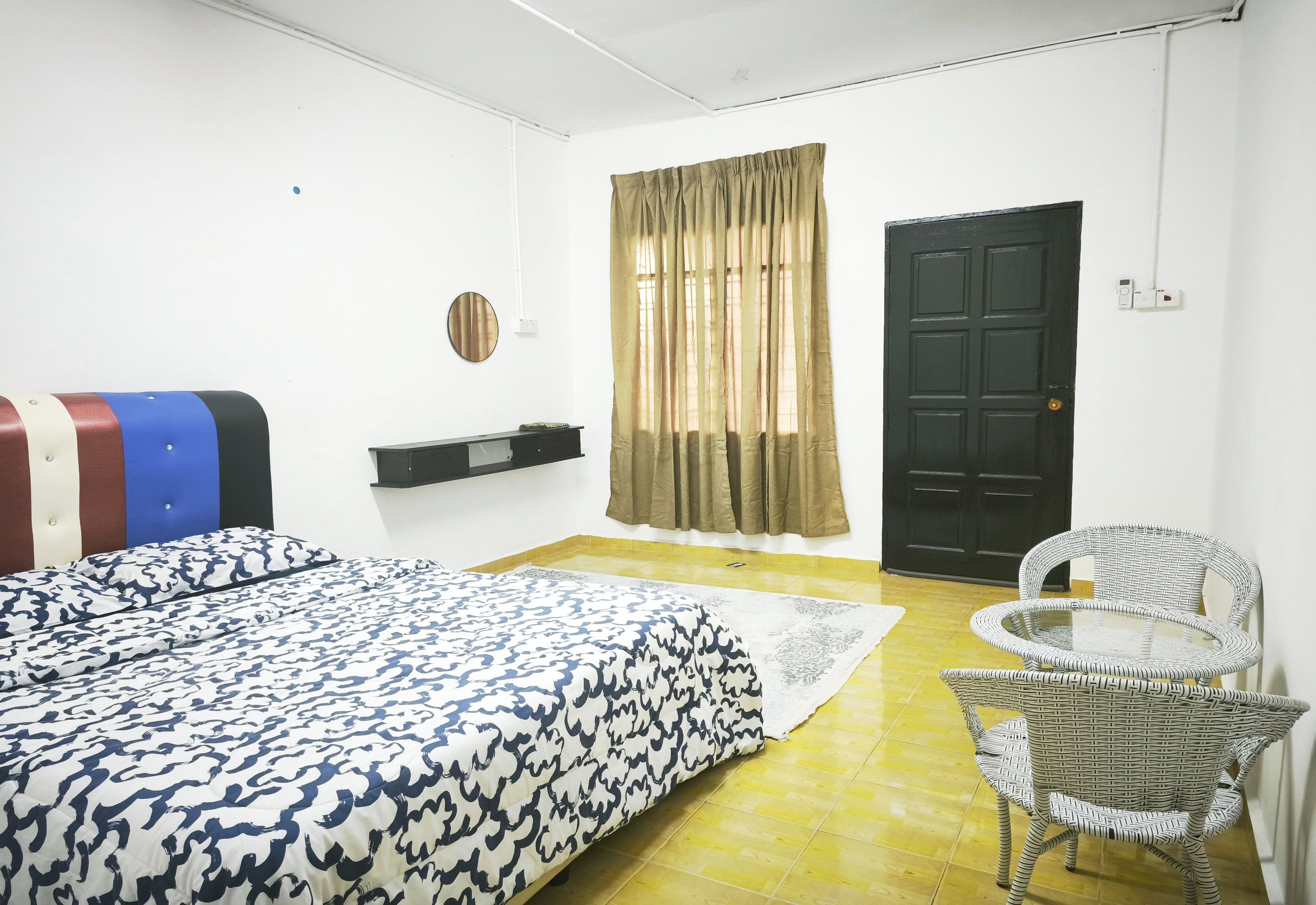 Un dormitorio con cama, una silla, una puerta y una ventana con cortinas.