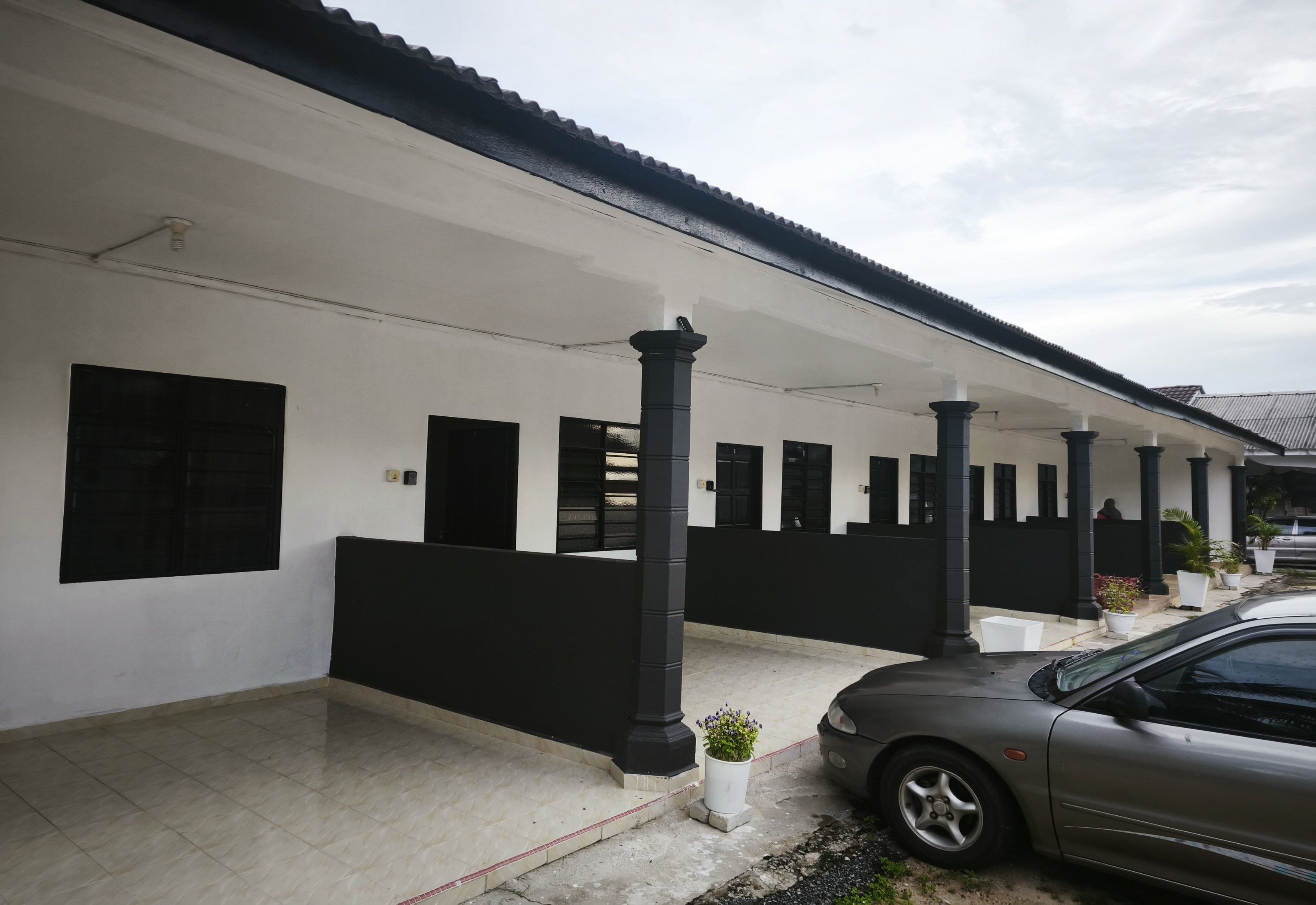 A building with a covered porch, columns, and a car parked in front.
