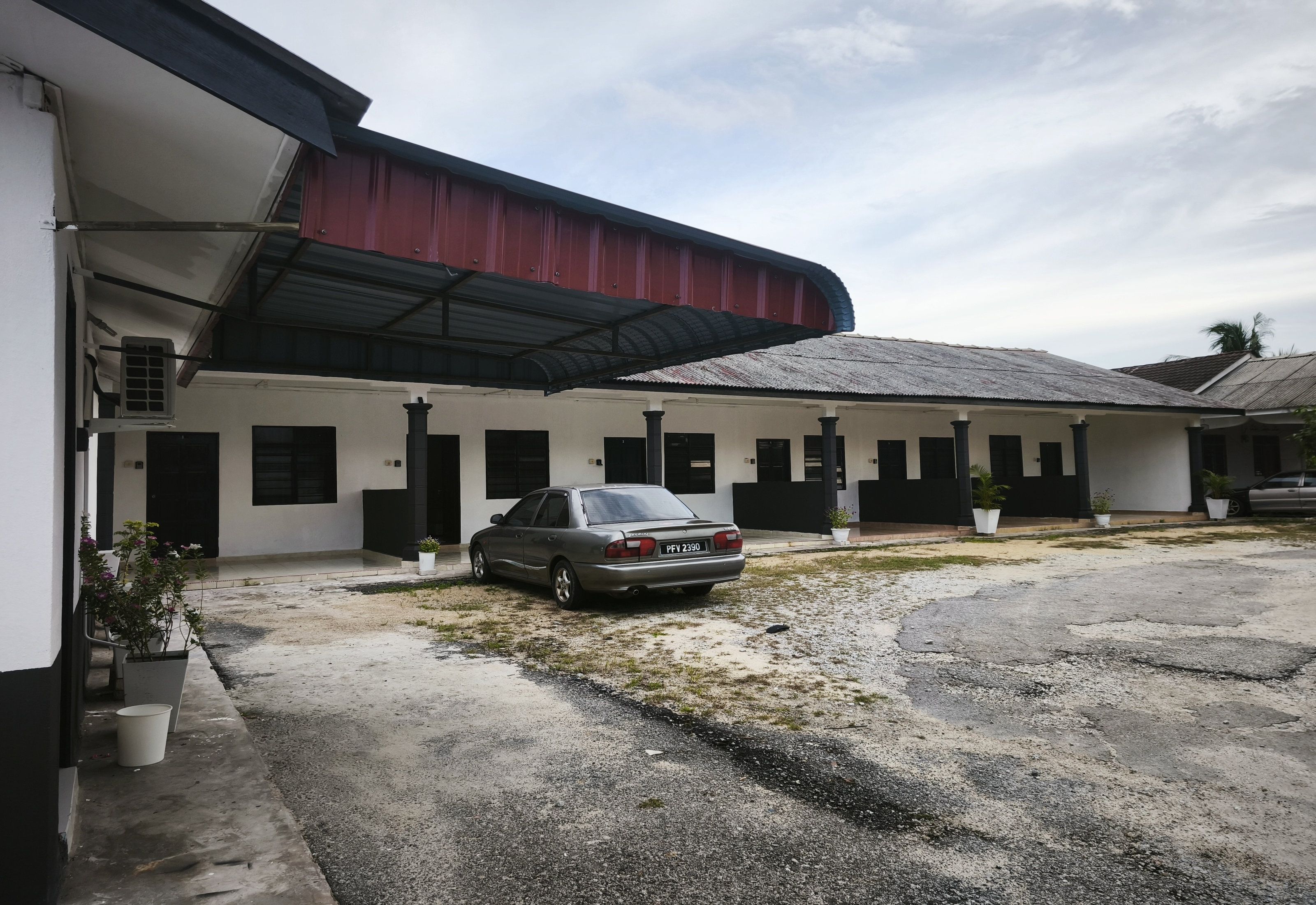 A building with a covered parking area and a parked car.