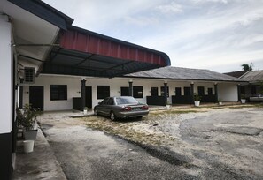 A building with a covered parking area and a parked car. - OYO 91244 Aufa Chalet (Kuala Terengganu)