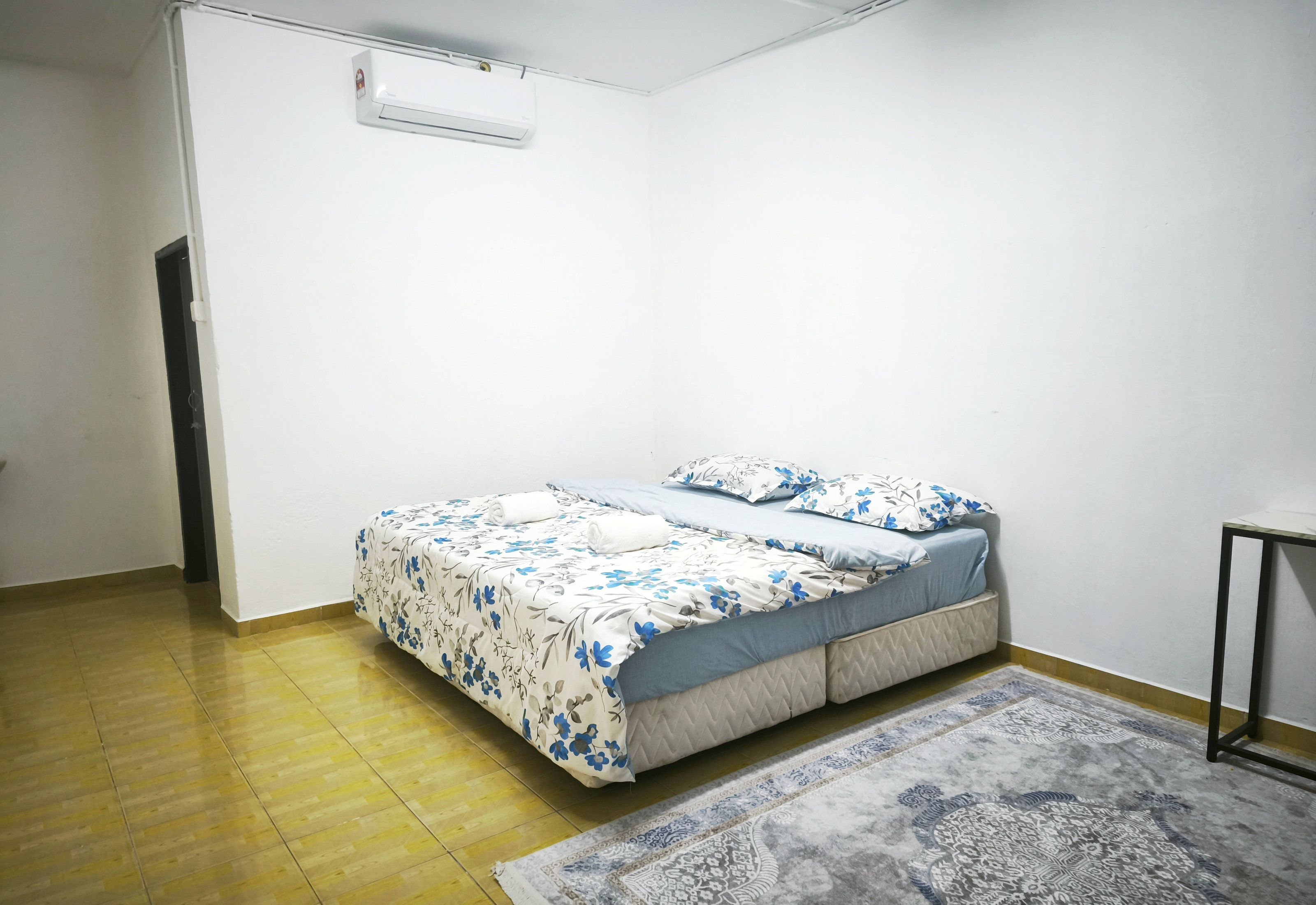 A bedroom with a bed, a rug, and an air conditioning unit.