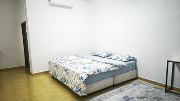 A bedroom with a bed, a rug, and an air conditioning unit.