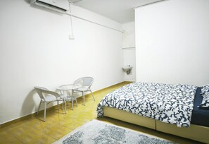 A room with a bed, a small table, two chairs, a wall-mounted light, and a patterned rug. - OYO 91244 Aufa Chalet (Kuala Terengganu)
