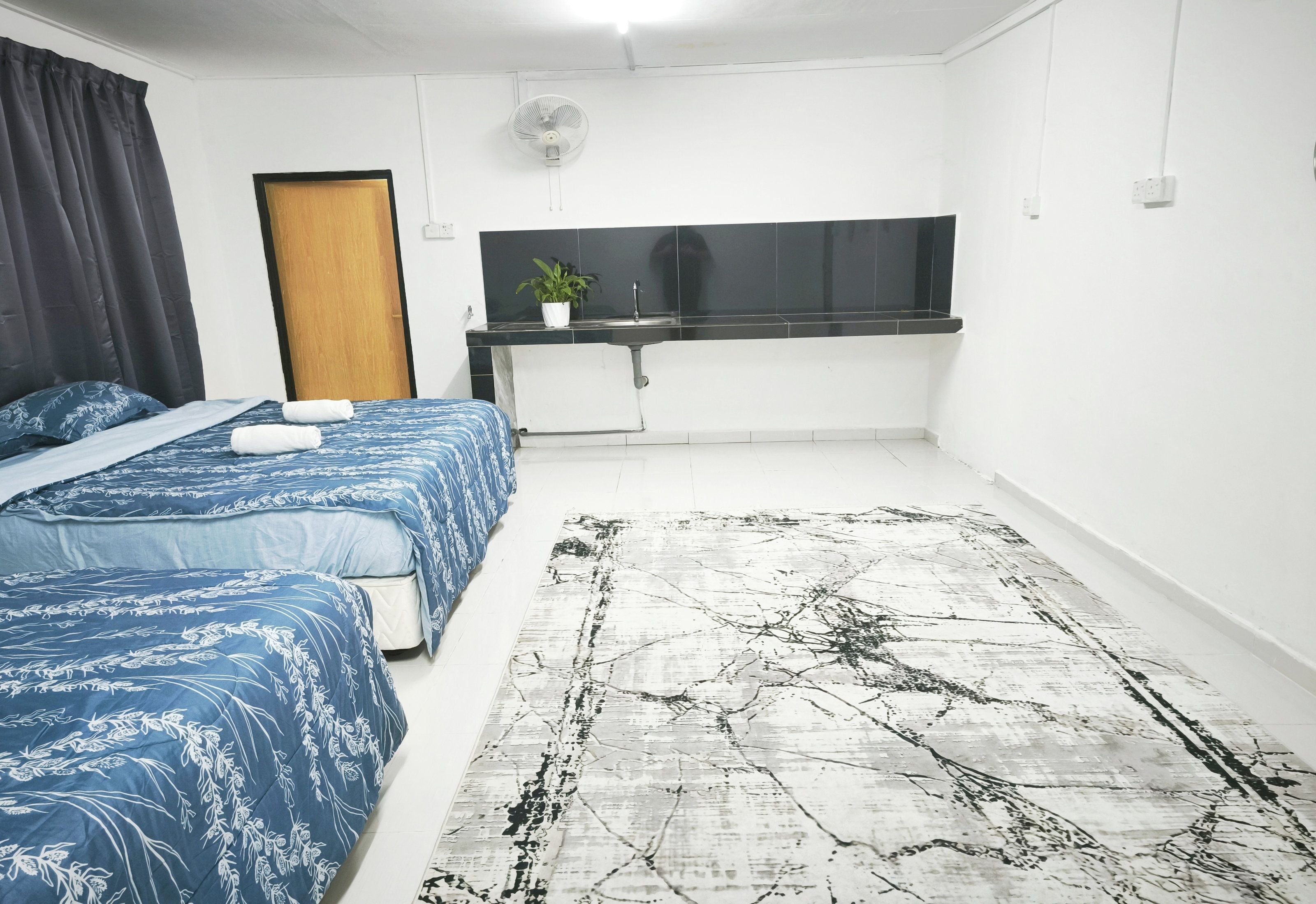 Une chambre à coucher avec un lit, un bureau, une plante en pot et un grand tapis.