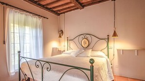 A bedroom with a metal bed frame, white bedding, a wooden ceiling, and two bedside lamps.