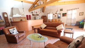 A spacious living room with a brown leather sofa, a glass coffee table, and a brown leather armchair. There is a wooden dining table and chairs in the background. - Holiday Home with Private Pool, Vagnas (Vagnas)