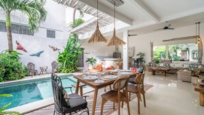 Een moderne woonkamer met zwembad, eethoek en keuken.