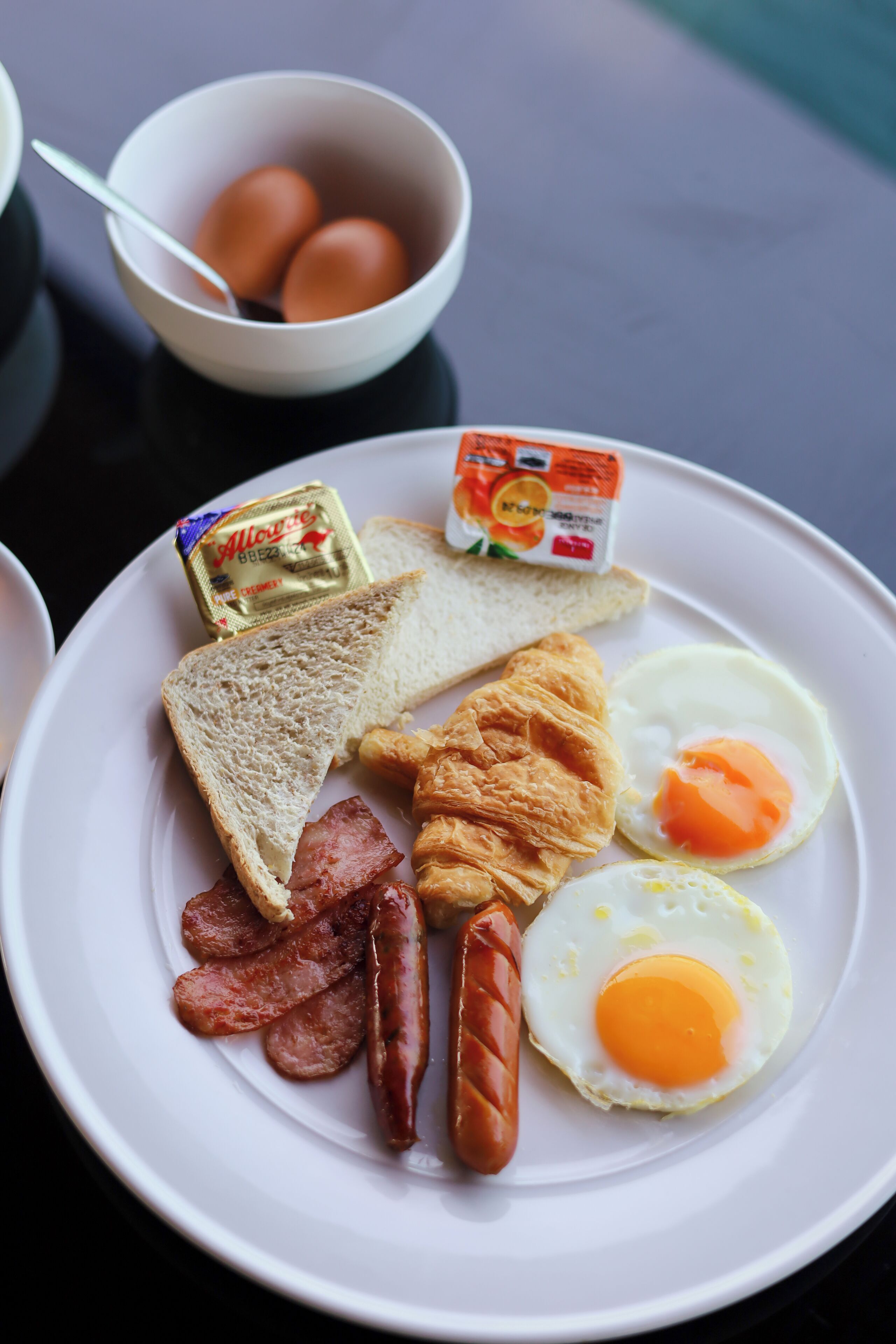 A breakfast plate with toast, eggs, sausages, and butter.