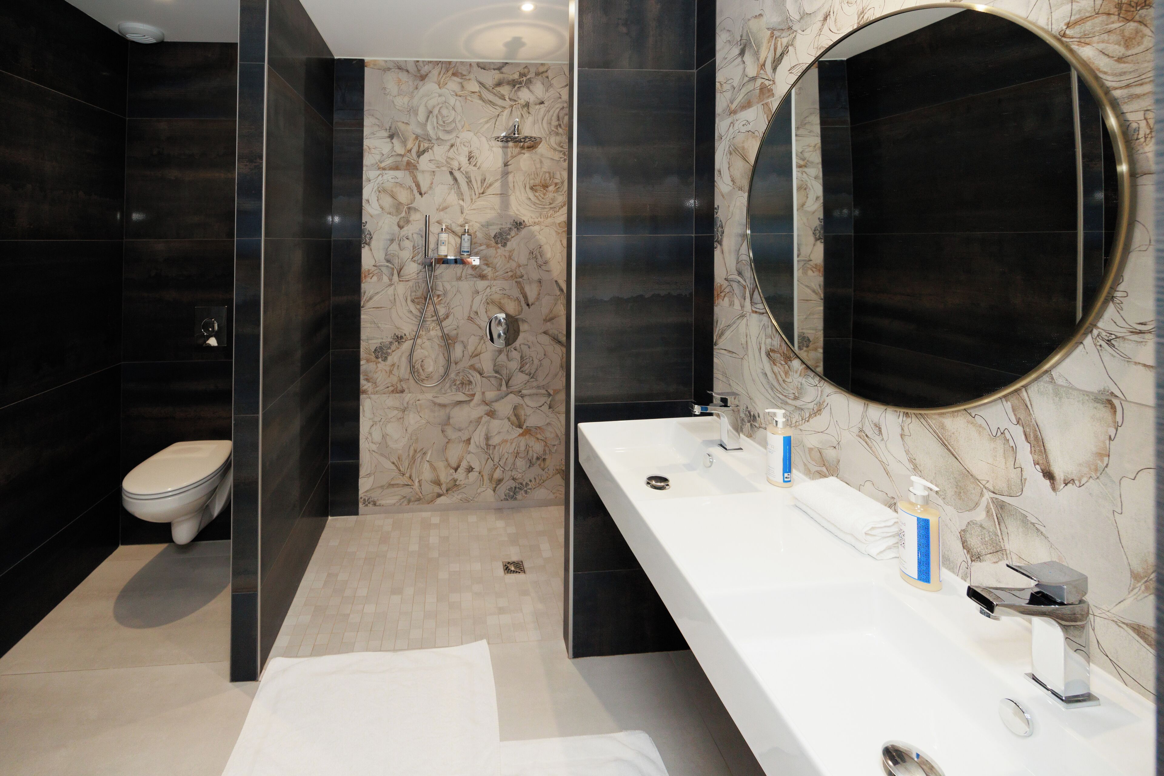 Un bagno moderno con uno specchio grande, un lavandino bianco e uno spazio doccia.