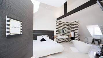 Un dormitorio moderno con una cama grande, una bañera blanca y un papel tapiz estampado.