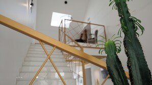 Un escalier avec une rampe jaune et un cactus au premier plan.