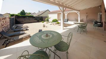 A covered patio area with a table and chairs, a barbecue grill, and a seating area with a sofa and chairs.