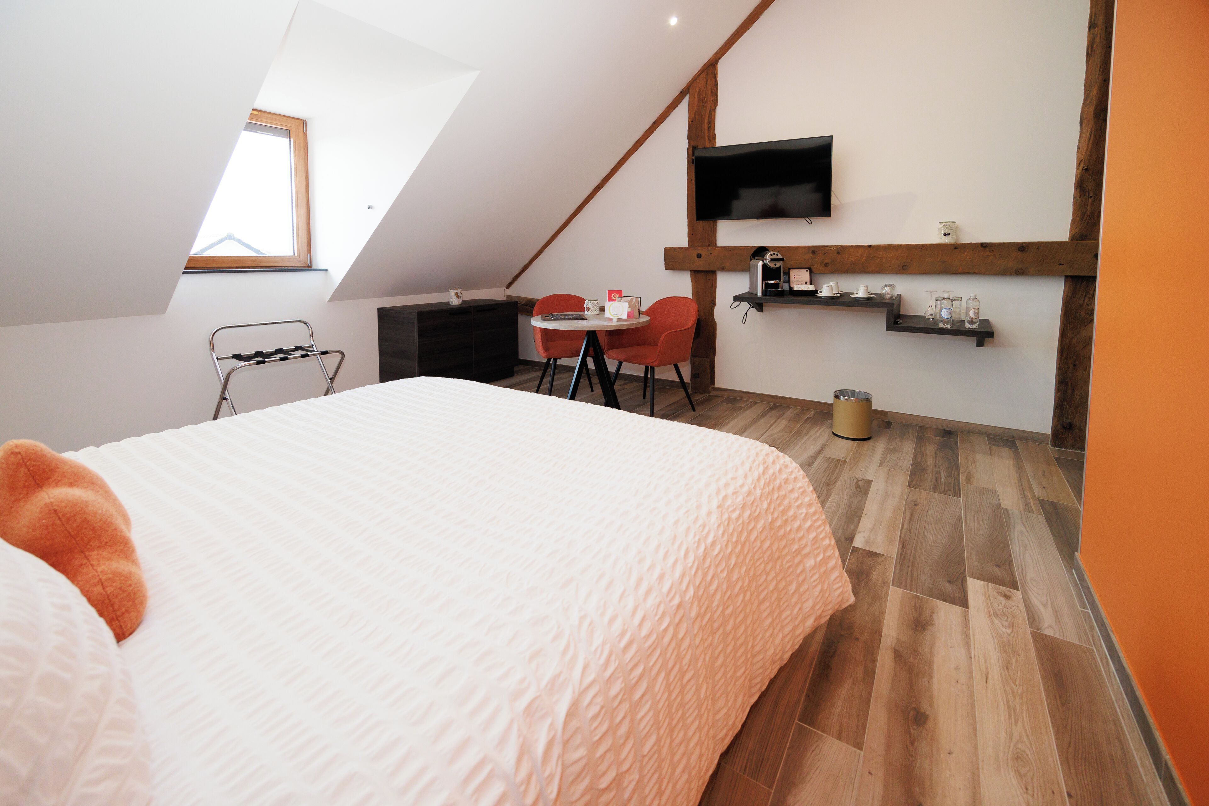 Un dormitorio con cama, escritorio, dos sillas, televisor y ventana.