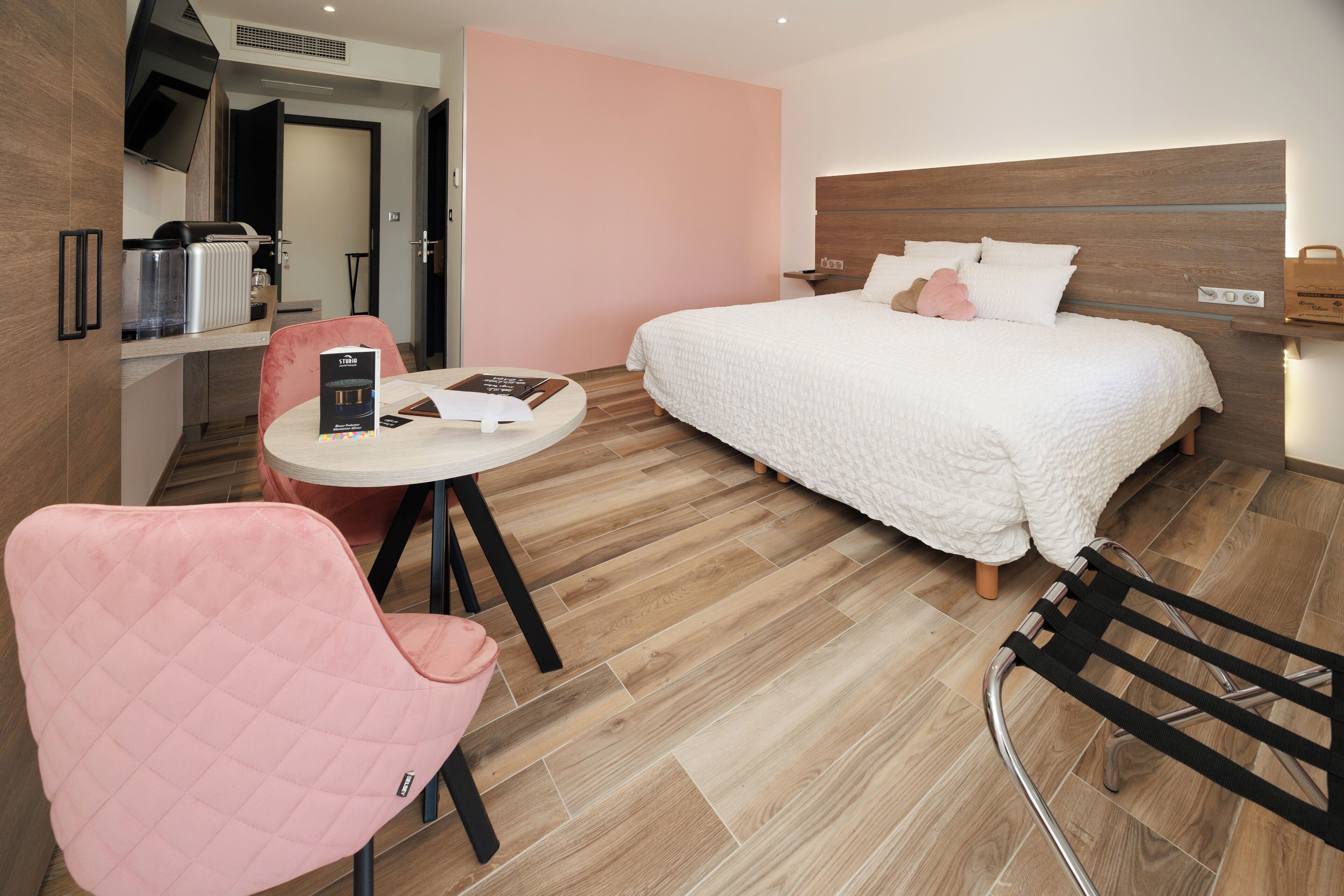 Une chambre d’hôtel moderne équipée d’un lit, d’un bureau, d’une chaise et d’une kitchenette.