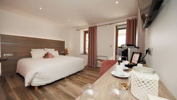 A modern hotel room with a large bed, a wooden headboard, a desk with a chair, and a window with curtains.