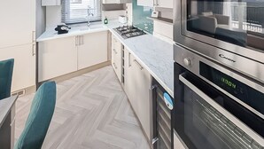 Une cuisine moderne équipée d’un four encastré, d’un four à micro-ondes et d’une cuisinière à gaz.
