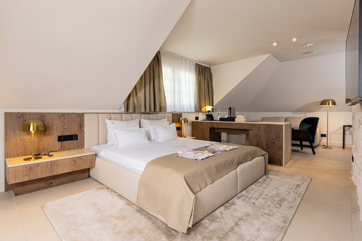 A modern hotel room with a large bed, a desk, and a chair.