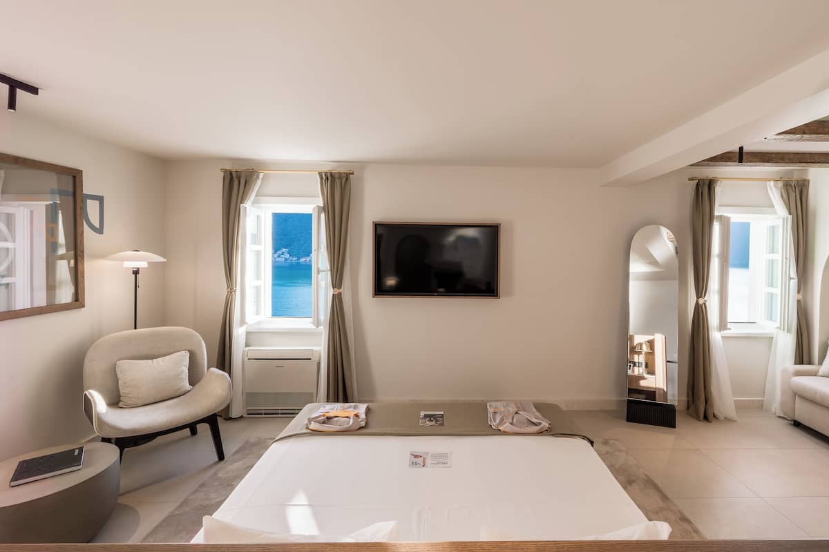A modern hotel room with a large bed, a chair, a desk, and a TV.