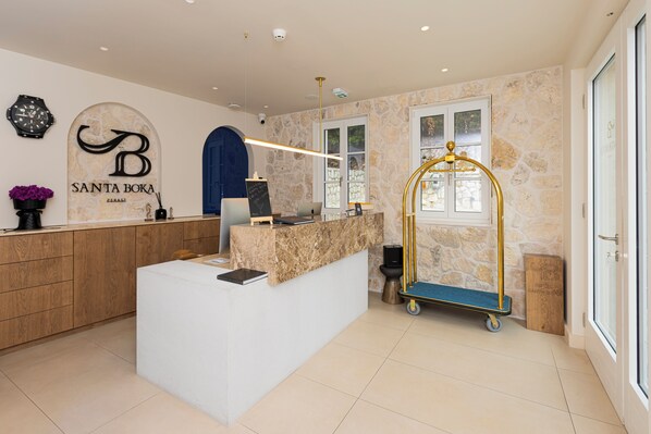 A reception area with a marble counter, a blue archway, and a stone wall backdrop. - Hotel & Restaurant Santa Boka (Perast)