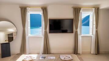 A hotel room with a bed, a TV mounted on the wall, and two windows with curtains.
