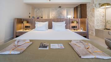 A hotel room with a large bed, two bedside tables with lamps, a stone accent wall, and a mirror.