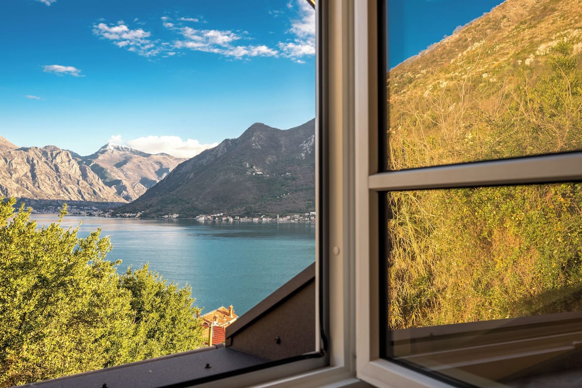 A view from a window overlooking a lake with mountains in the background.