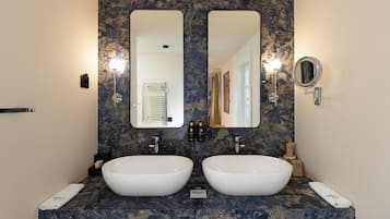 Un baño con dos lavamanos, un espejo grande y un espejo redondo pequeño.