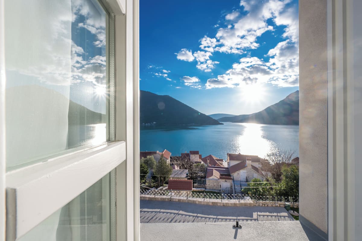 A view from a window overlooking a lake with mountains in the background.