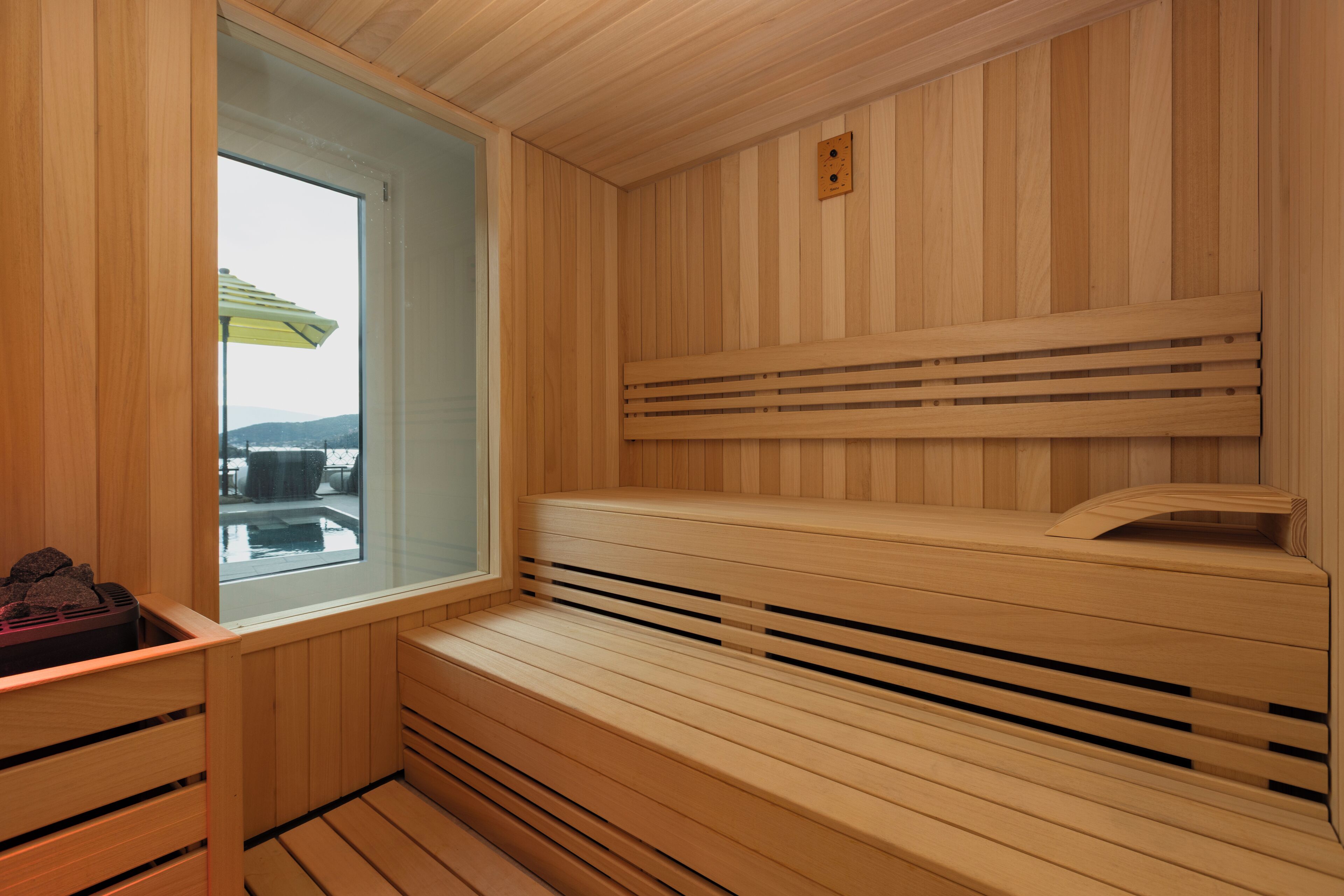 Un sauna en bois, avec un banc, une fenêtre et une vue sur l’extérieur.