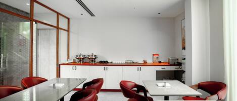 Una cocina moderna con armarios blancos, una encimera de madera y sillas rojas alrededor de una mesa central.