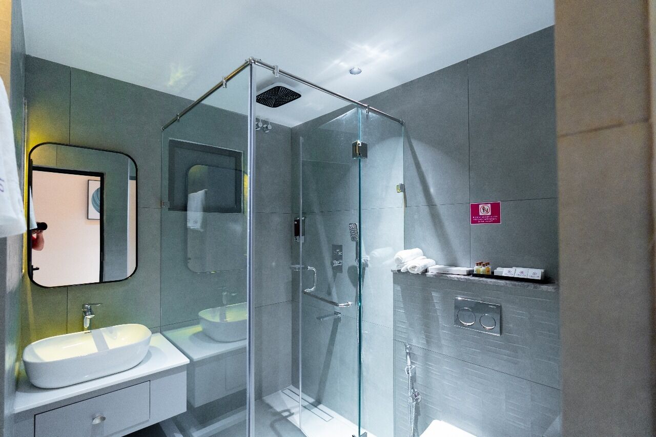 Un bany modern amb dutxa de vidre, un lavabo i un mirall.