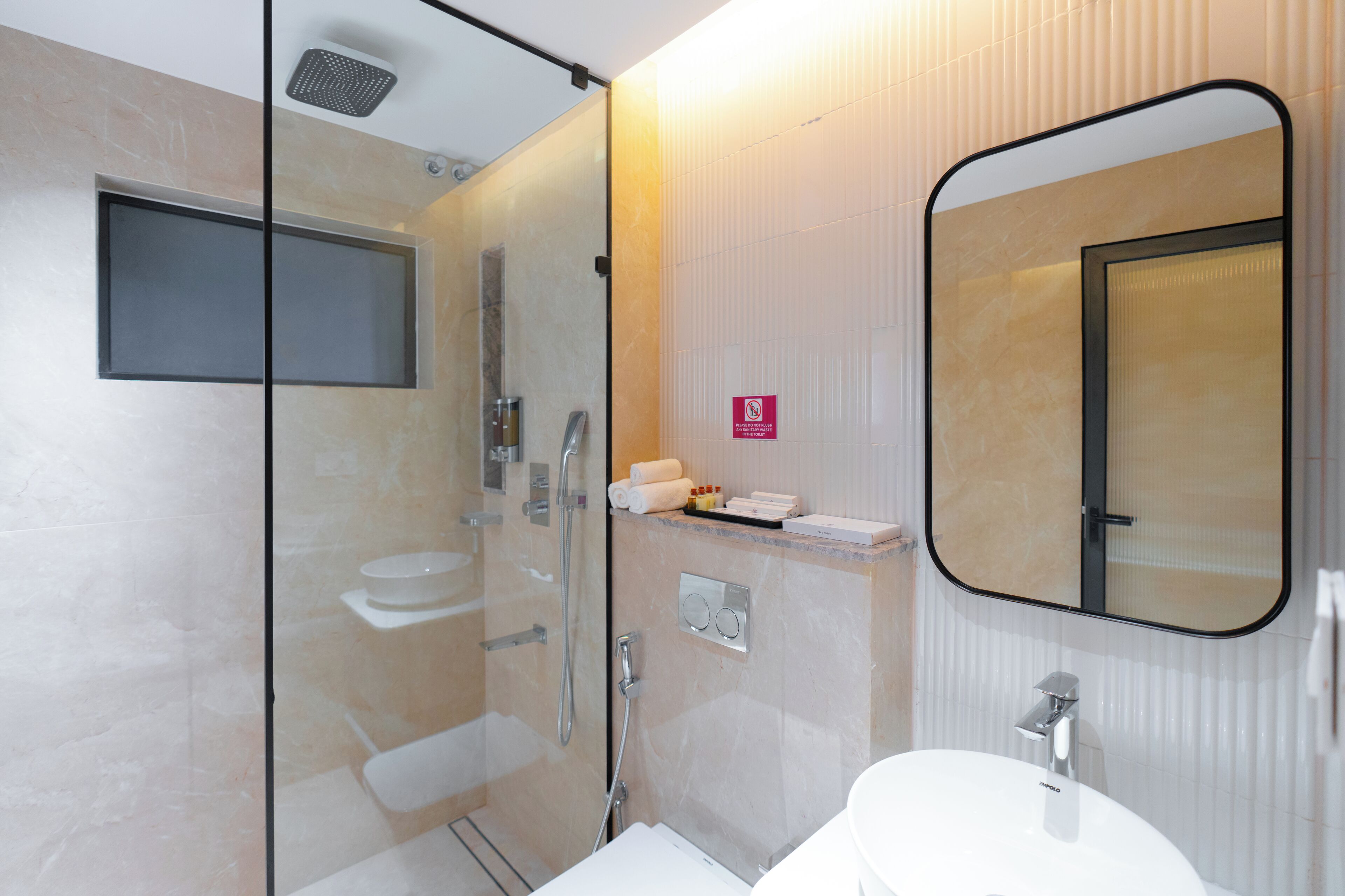 A modern bathroom with a glass-enclosed shower, a toilet, and a sink with a mirror above.