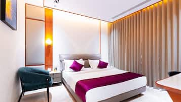 A modern hotel room with a large bed, a desk, and a chair.