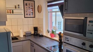 A modern kitchen with stainless steel appliances, a coffee maker, and a clock on the wall. - Cozy apartment with central location directly at the market in Hainichen (Hainichen)