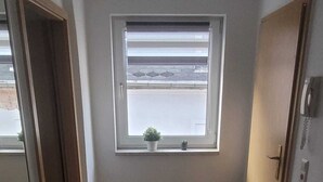 A narrow hallway with a window, a small potted plant, and a door. - Cozy apartment with central location directly at the market in Hainichen (Hainichen)