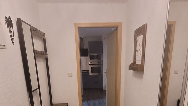 A hallway with wooden flooring leading to a kitchen area. - Cozy apartment with central location directly at the market in Hainichen (Hainichen)
