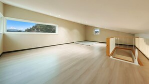 Una habitación amplia con un gran ventanal, suelo de madera y un banco empotrado.