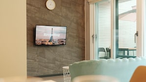Una sala de estar con un televisor de pantalla plana montado en una pared con textura, un sofá y una mesita auxiliar.