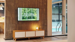 Un interior moderno con un televisor montado en una pared con textura que muestra la palabra 'Recording'.