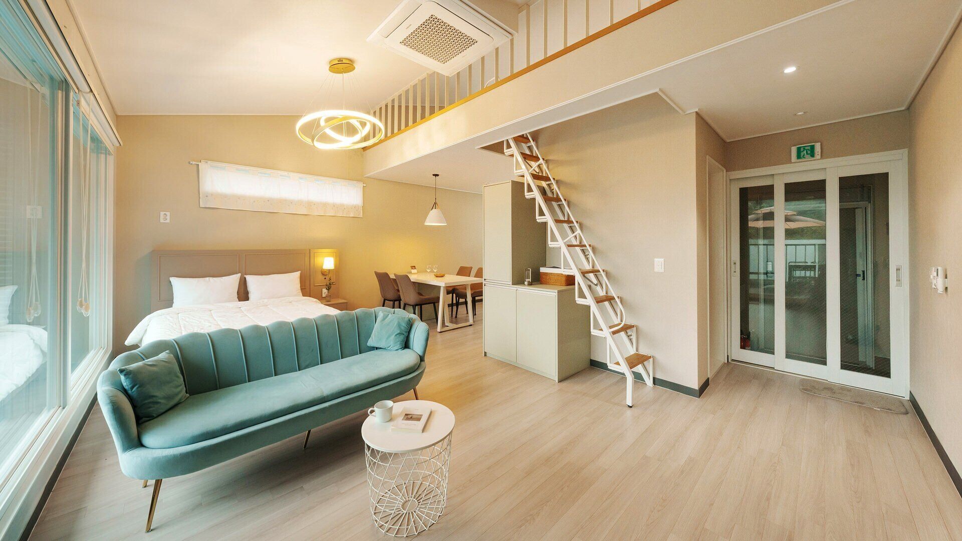 Una habitación de hotel moderna con una cama, un sofá, una zona de comedor y una escalera.