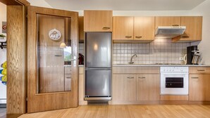 Una cocina moderna con armarios de madera, un refrigerador de acero inoxidable, horno empotrado y salpicadero de azulejos.