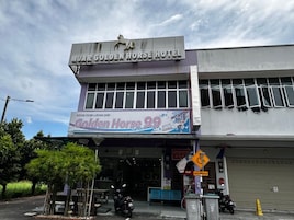 Un edificio con un cartel que dice 'NUK GOLDEN HORSE HOTEL' y un banderín que anuncia 'Golden Horse 99 Super Wash'.